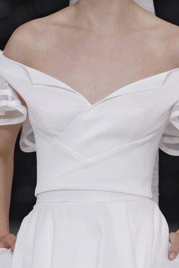 femme dans une robe de mariée à col sur un podium de défilé