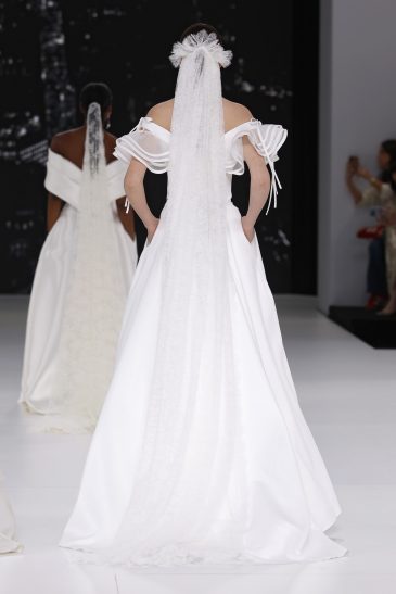 femme dans une robe de mariée à col sur un podium de défilé