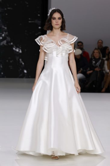 femme dans une robe de mariée à col sur un podium de défilé