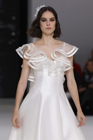 femme dans une robe de mariée à col sur un podium de défilé