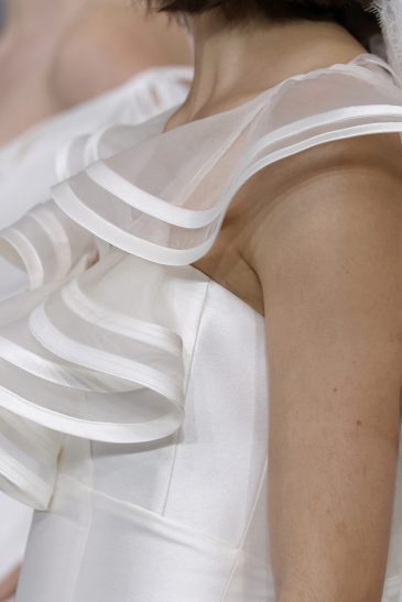 femme dans une robe de mariée à col sur un podium de défilé