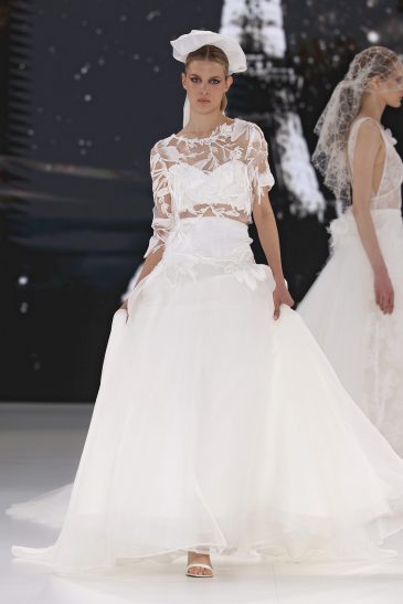 femme dans une robe de mariée avec un top en dentelle et une jupe sur un podium de défilé