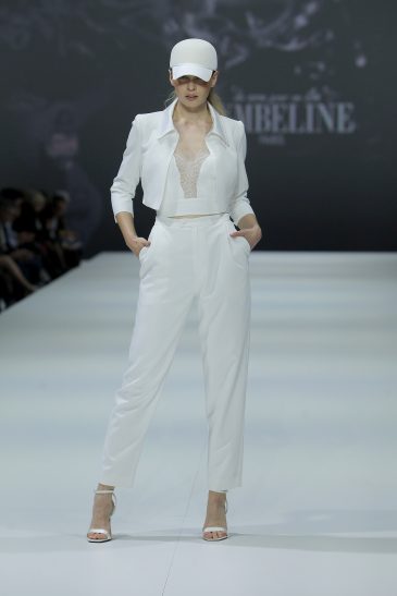 femme dans un ensemble de mariée veste, top et pantalon sur un podium de défilé