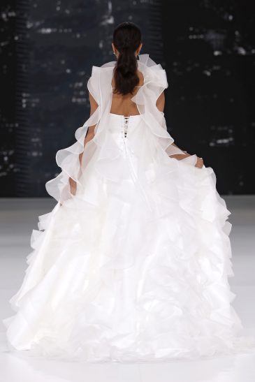 femme dans une robe de mariée à volants sur un podium de défilé