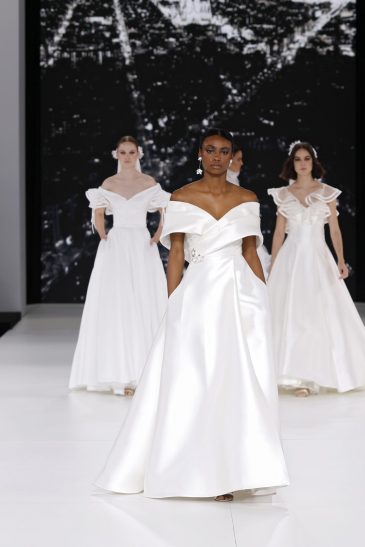 femme dans une robe de mariée à col sur un podium de défilé