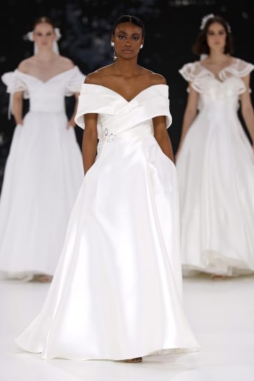 femme dans une robe de mariée à col sur un podium de défilé
