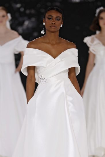 femme dans une robe de mariée à col sur un podium de défilé