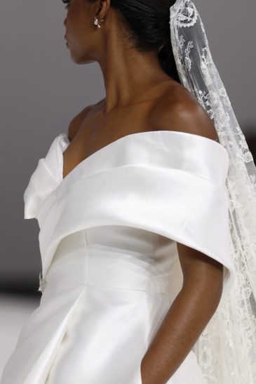 femme dans une robe de mariée à col sur un podium de défilé