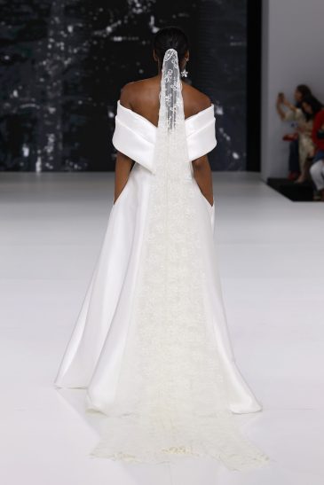 femme dans une robe de mariée à col sur un podium de défilé