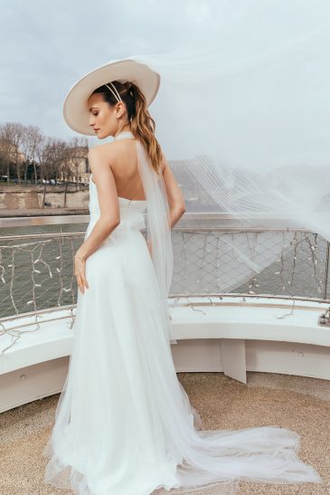 femme dans une robe de mariée glamour avec un chapeau à Paris