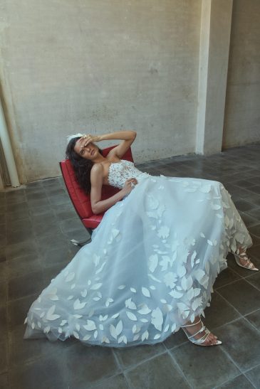 femme sur un fauteuil, habillée d'une robe de mariée glamour en matière façonnée