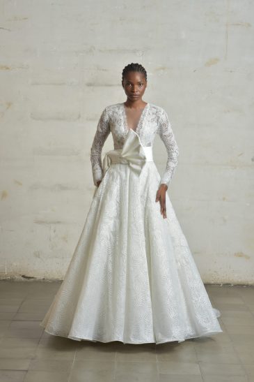 femme portant une robe de mariée princesse glamour et manches longues, avec un joli nœud au niveau de la taille