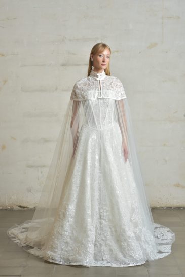 femme habillée d'une robe de mariée princesse brillante, accompagnée d'une jolie cape