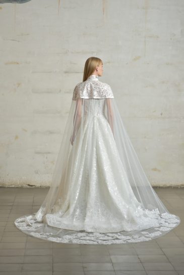 femme habillée d'une robe de mariée princesse brillante, accompagnée d'une jolie cape