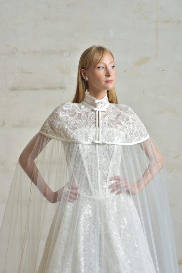 femme habillée d'une robe de mariée princesse brillante, accompagnée d'une jolie cape
