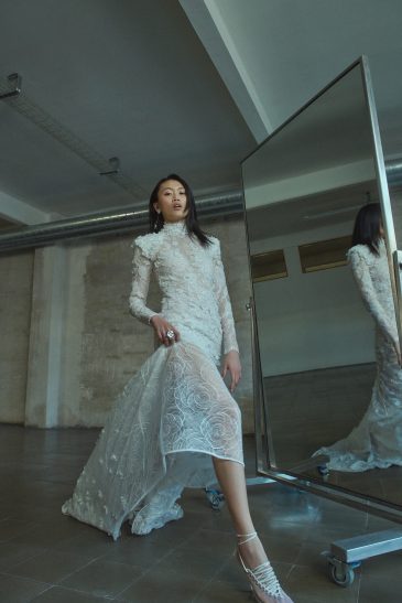 femme habillée d'une robe de mariée sirène glamour, avec une traîne et des manches longues