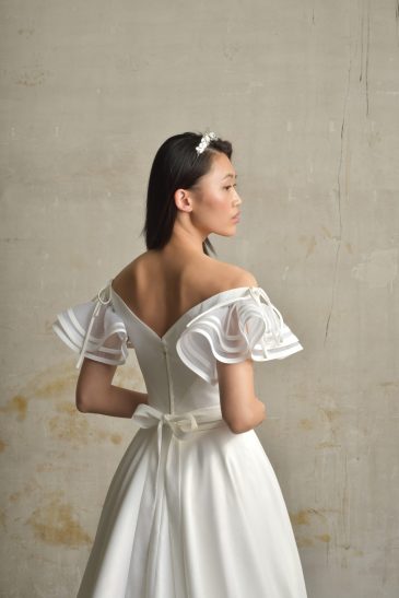 femme dans une robe de mariée princesse en taffetas broché dans un studio