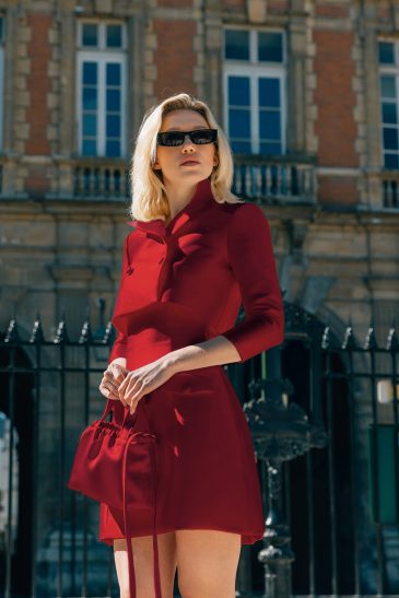 femme dans une robe de soirée courte rouge en mikado dans un parc à Paris