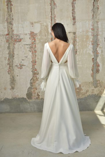 femme dans une robe de mariée épurée et fluide avec des manches longues amovibles
