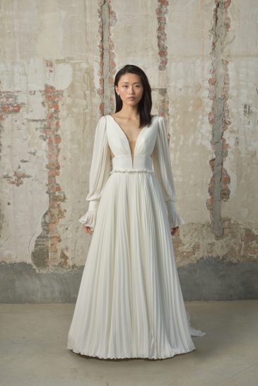 femme dans une robe de mariée épurée et fluide avec des manches longues amovibles