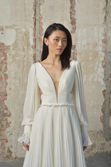 femme dans une robe de mariée épurée et fluide avec des manches longues amovibles