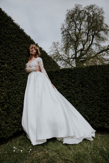 femme avec une robe de mariée princesse à manches longues en dentelle et en mikado