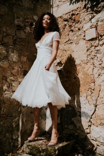 femme avec une robe de mariée courte bohème chic en dentelle et en plumetis