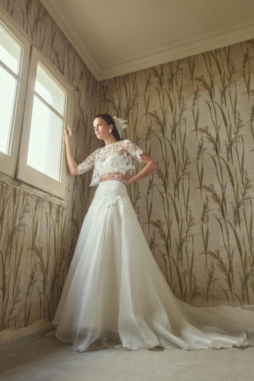 femme habillée d'une tenue de mariée composée d'une jules longue et volumineuse, d'un top bandeau et d'un top court en raphia