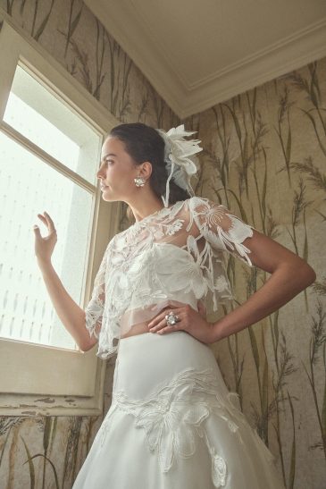 femme habillée d'une tenue de mariée composée d'une jules longue et volumineuse, d'un top bandeau et d'un top court en raphia