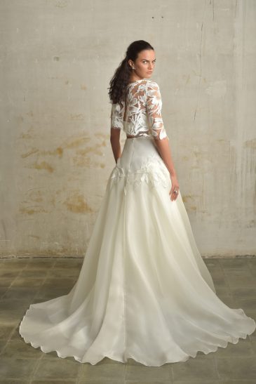 femme habillée d'une tenue de mariée composée d'une jules longue et volumineuse, d'un top bandeau et d'un top court en raphia