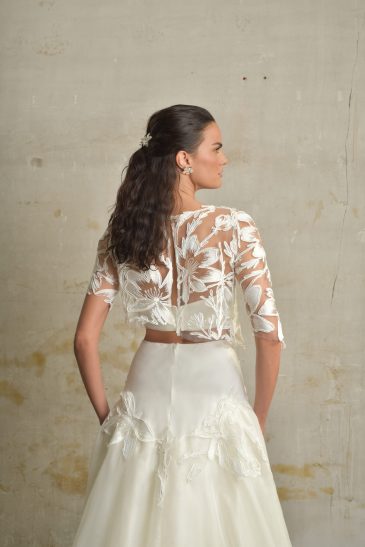 femme habillée d'une tenue de mariée composée d'une jules longue et volumineuse, d'un top bandeau et d'un top court en raphia